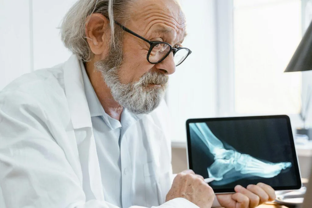 orthopedic surgeon in a white coat discussing X-ray results on a tablet and illustrating AO fracture classification system.