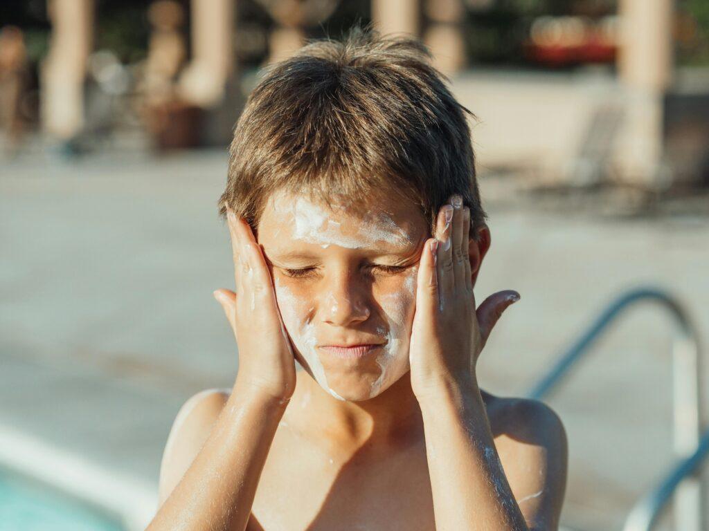 SS on boy face, benefits of sunscreen in children, protection from sun and skin cancer, which one should use.