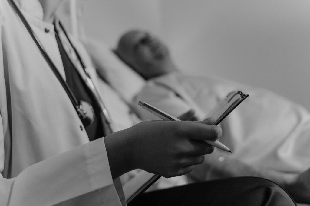 A doctor takes notes while consulting a pre operative patient in a hospital setting, taking detailed history.